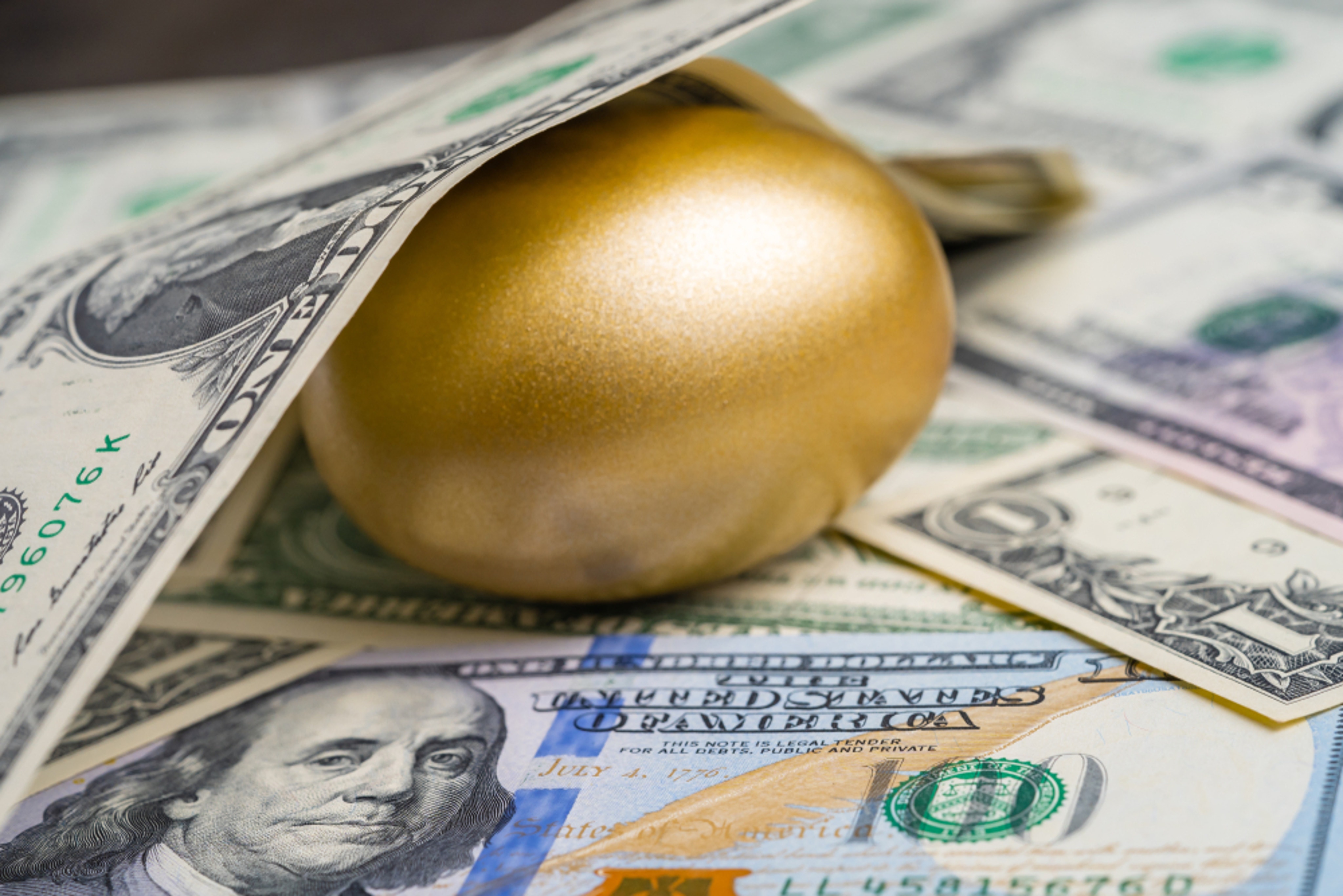 Shiny,Golden,Egg,Under,Pile,Of,Us,America,Dollar,Banknotes