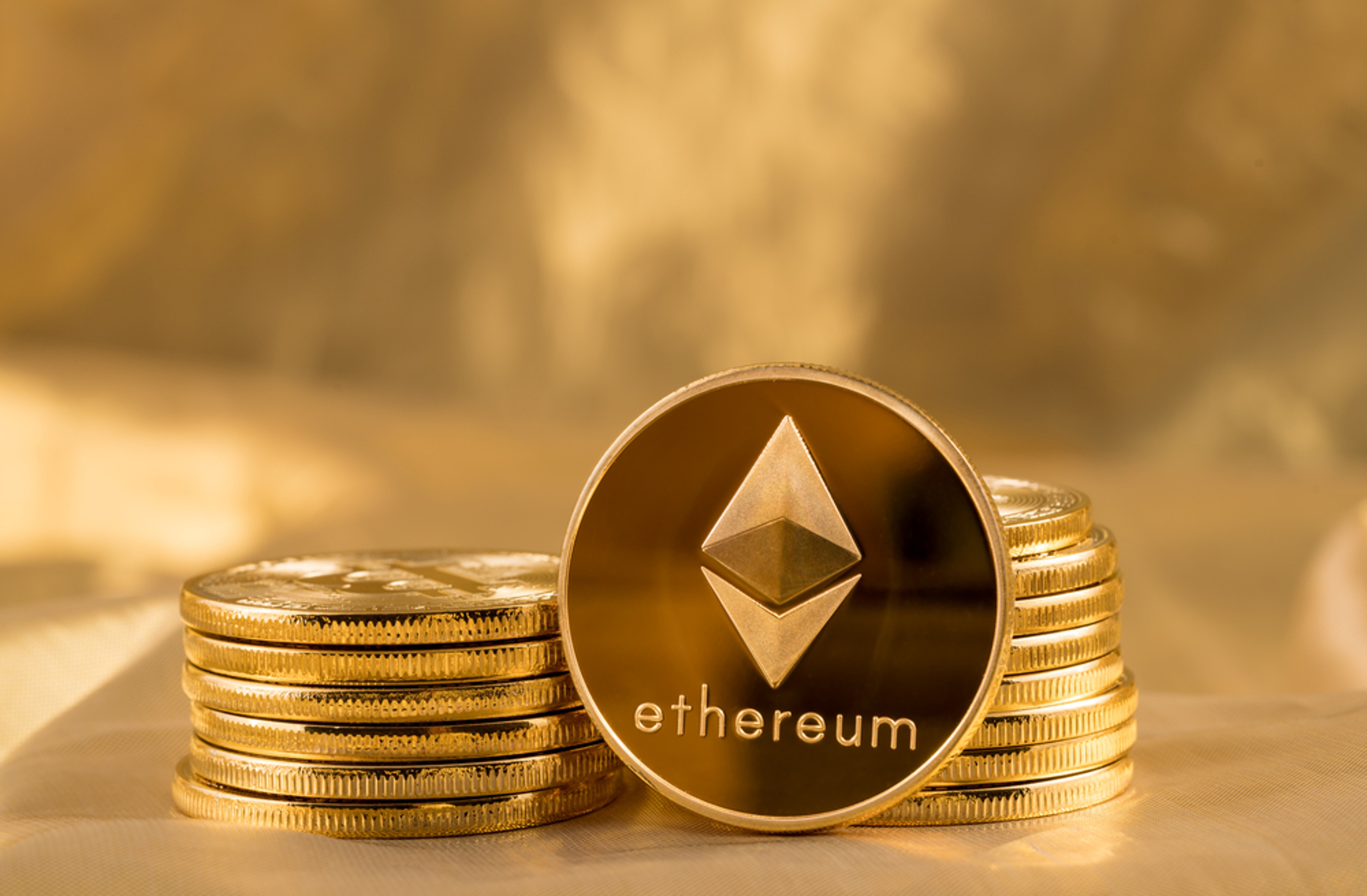 Stack,Of,Ether,Coins,Or,Ethereum,On,Gold,Background,To